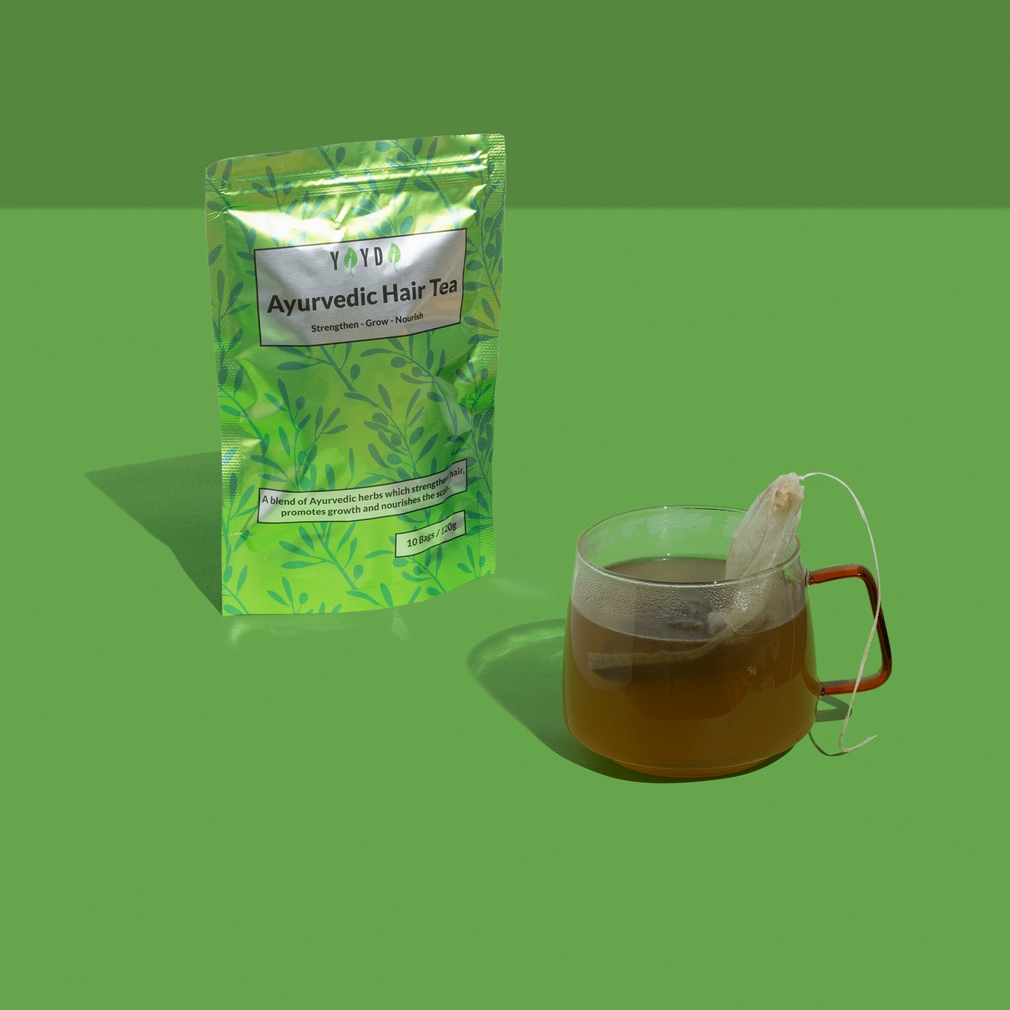Green hair tea bag and a glass mug with tea